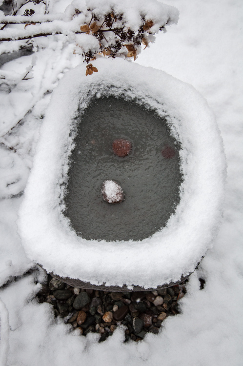 A stone bird bath on our back patio bedecked with snow.